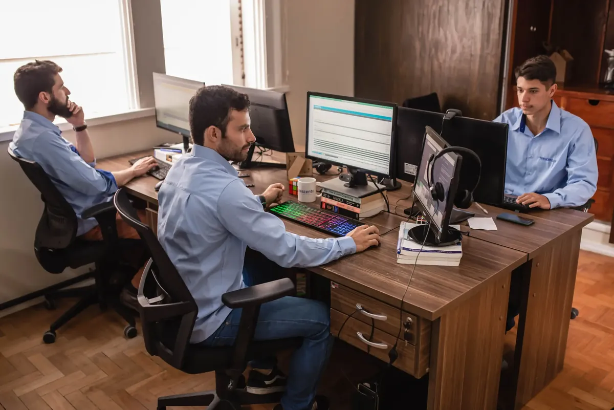 Equipe de analistas trabalhando em múltiplos monitores em escritório de wealth management