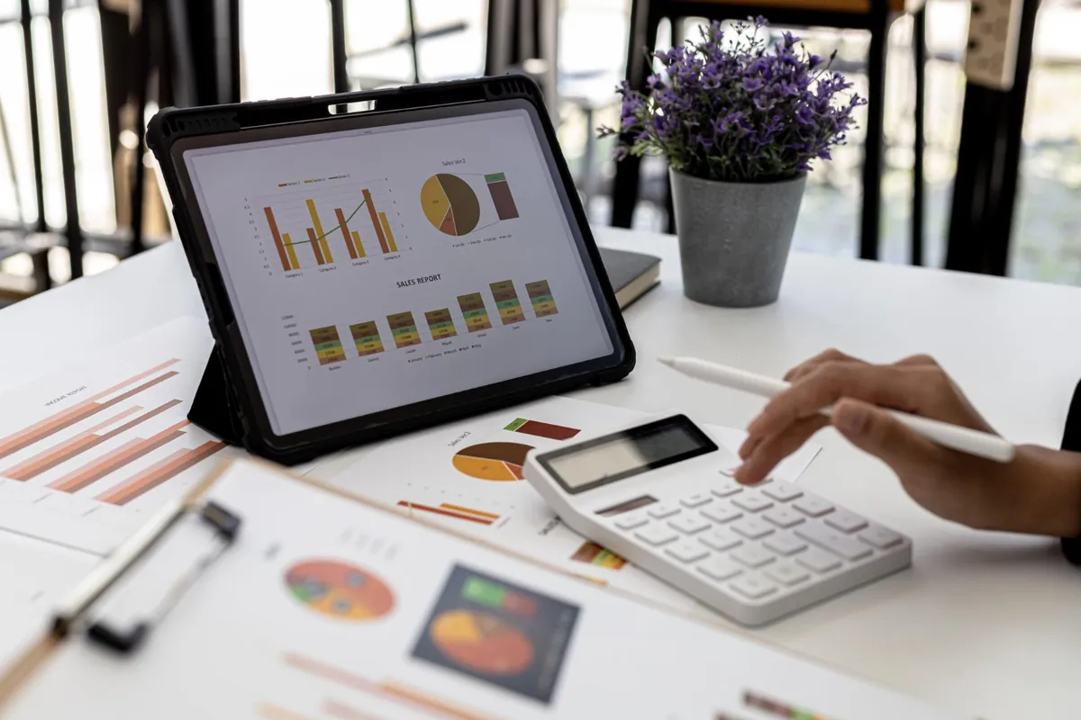 Como analisar indicadores financeiros? Pessoa analisando indicadores financeiros em um tablet com gráficos de barras e pizza