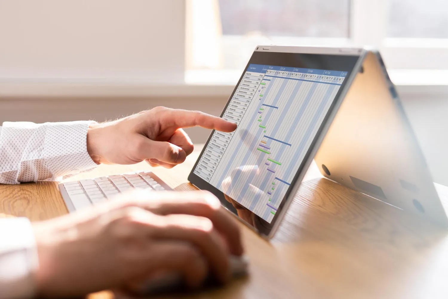 Gestão de fluxo de caixa: o que é, desafios, como organizar e boas práticas para médias empresas Profissional analisa planilha financeira em laptop com gráfico de barras, representando processos de gestão de fluxo de caixa