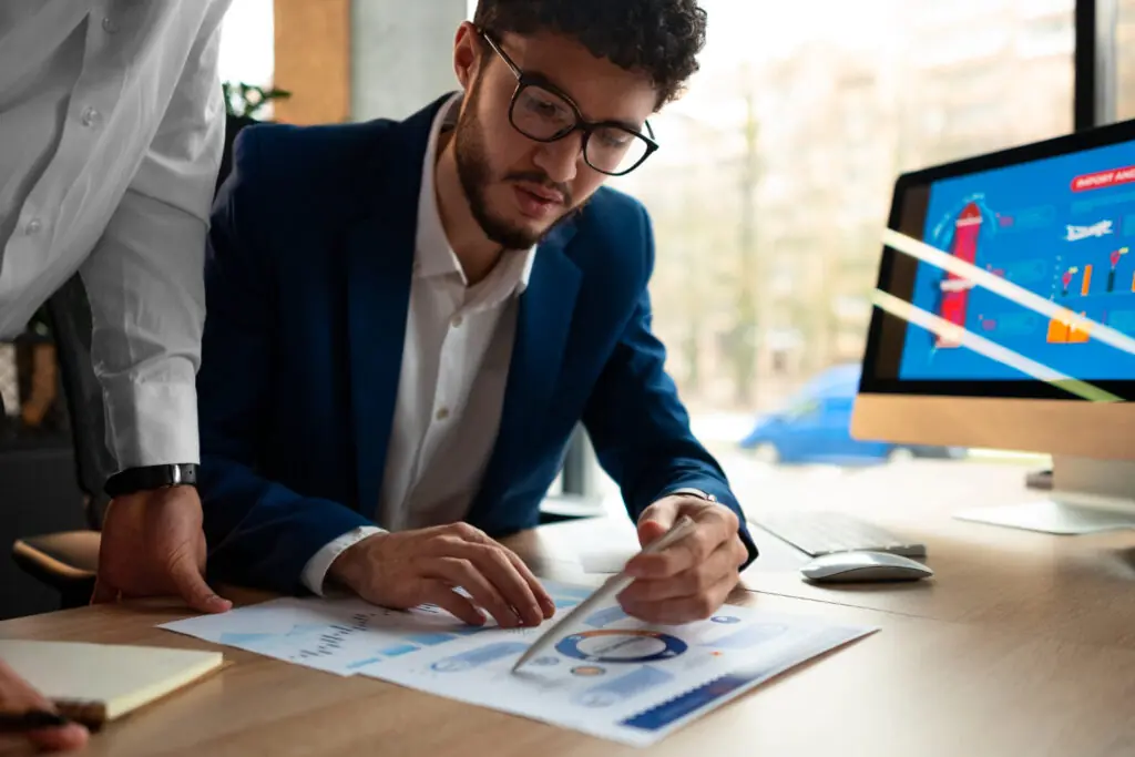 Executivo analisando relatórios gráficos em mesa como parte do controle financeiro empresarial da empresa